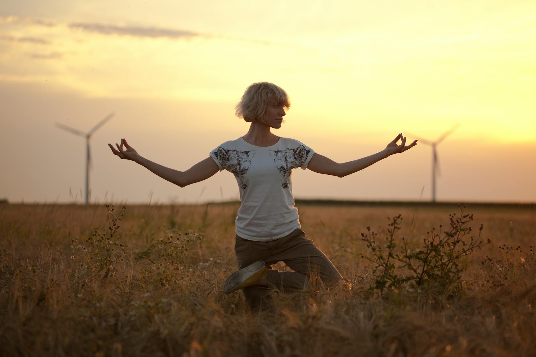 Person in a calming yoga pose on a paddleboard at sunset.